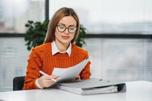 contento sorridente attività commerciale donna a opera parlando su Telefono, seduta a sua Lavorando posto nel ufficio, copia spazio foto