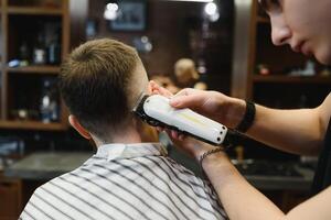 fabbricazione taglio di capelli Guarda Perfetto. giovane barbuto uomo ottenere taglio di capelli di parrucchiere mentre seduta nel sedia a barbiere. foto