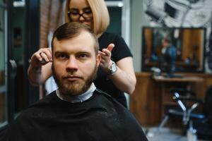 barbiere donna taglio uomo capelli a il barbiere. donna Lavorando come un' parrucchiere. piccolo attività commerciale concetto foto