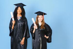 Due giovane donne festeggiare loro la laurea con diplomi foto