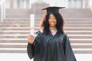 studente laureato afroamericano allegro con il diploma in sua mano foto