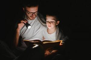 padre e il suo poco figlio lettura di andare a dormire storia a casa. foto
