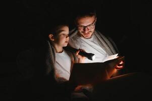 padre e il suo poco figlio lettura di andare a dormire storia a casa. foto