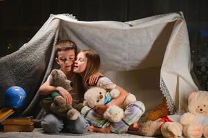 bambini ragazzo e ragazza giocando e impaurire ogni altro con torcia elettrica nel tenda a notte foto