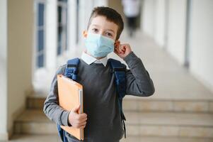 formazione scolastica, pandemia e Salute concetto - alunno ragazzo indossare viso protettivo medico maschera per protezione a partire dal virus malattia a scuola. foto