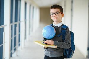 scolaro con cartella e libri nel il scuola. formazione scolastica concetto. indietro per scuola. schoolkid andando per classe. elegante ragazzo con zaino. ragazzo pronto per studia. foto