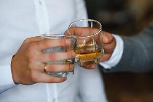 maschio mani detiene bicchieri con whisky su nero sfondo. Saluti, vicino su. foto