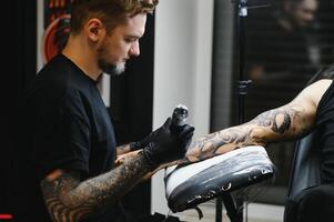 tatuatore con il suo macchina tatuaggio su il braccio con il design disegnato, concetto di arte e design foto