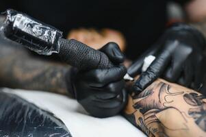 tatuaggio salone. il tatuaggio maestro è tatuaggio un' uomo. tatuaggio macchina, sicurezza e igiene a opera. avvicinamento, colorato, tatuatore. foto