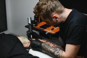 professionale tatuaggio artista Lavorando nel il suo tatuaggio studio. foto