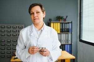 ritratto di esperto pensionato pensionato infezione specialista donna consultare corona virus paziente hold pillole bicchiere acqua indossare stetoscopio. foto
