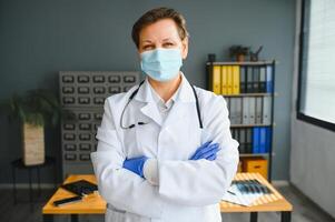più vecchio femmina medico indossare viso maschera e bianca medico cappotto in piedi nel Ospedale. ritratto foto