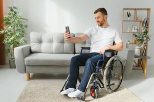 Disabilitato uomo utilizzando moderno smartphone per conversazione mentre soggiorno a casa. concetto di le persone, invalidità e tecnologia. foto