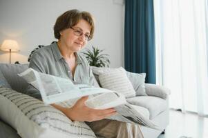 età e persone concetto - contento anziano donna lettura giornale a casa foto