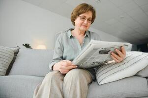 età e persone concetto - contento anziano donna lettura giornale a casa foto