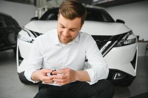 sì, quello è mio nuovo macchina. cliente nel auto concessionaria. giovane uomo con chiavi nel mano. foto