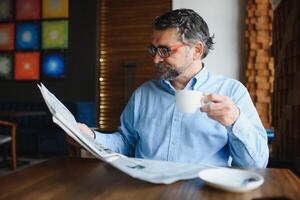 giornale nel il mattina. anziano uomo d'affari a il suo ufficio equitazione giornali. foto