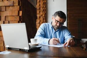 attività commerciale, tecnologia e persone concetto , anziano uomo d'affari con il computer portatile computer potabile caffè a moderno bar. foto