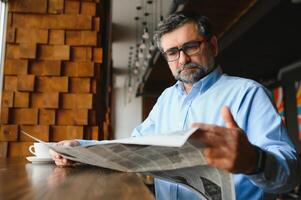 giornale nel il mattina. anziano uomo d'affari a il suo ufficio equitazione giornali. foto