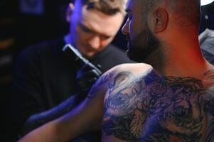 tatuaggio artista dimostra il processi di ottenere nero tatuaggio con dipingere. maestro lavori nel nero sterile guanti foto