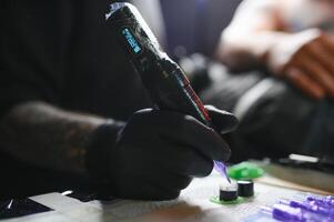 ritratto di un' tatuaggio maestro mostrando un' processi di creazione tatuaggio su un' mano sotto il lampada leggero foto