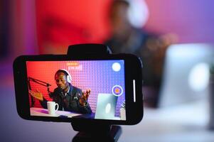 bello giovane africano americano uomo parlando in microfono mentre registrazione Radio mostrare foto