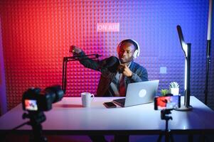 bello giovane africano americano uomo parlando in microfono mentre registrazione Radio mostrare foto