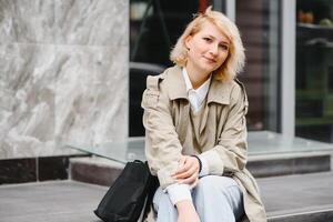 bellissimo elegante donna avendo bene moda Abiti a piedi su strada e potabile alcuni caffè nel tazza porta via con bene estate umore vicino strada bar. foto