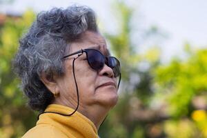 avvicinamento Visualizza lato di viso anziano donna in piedi e guardare nel sua giardino. foto