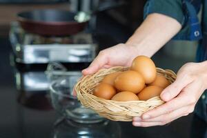 avvicinamento foto di il giovane dell'uomo mani Tenere un' cestino pieno di uova biologico nel il cucina per preparare cibo. uova siamo benefico per il corpo. proteina aiuta il corpo sano. Salute Alimenti concetto