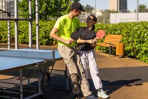 contento uomo con il suo figlia giocando ping pong nel parco foto