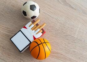 fumo o gli sport. sport palla e imballare di sigarette su tavolo sfondo. superiore Visualizza foto