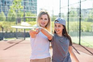 madre e figlia siamo giocando badminton al di fuori nel il cortile su estate caldo giorno foto