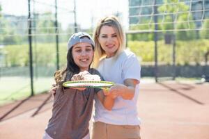 madre e figlia siamo giocando badminton al di fuori nel il cortile su estate caldo giorno foto