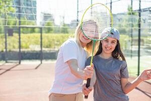 madre e figlia siamo giocando badminton al di fuori nel il cortile su estate caldo giorno foto