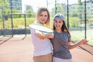 madre e figlia siamo giocando badminton al di fuori nel il cortile su estate caldo giorno foto