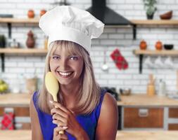 giovane sorridente bionda capocuoco con sua colorato cucchiaio in posa su neutro sfondo foto