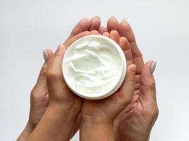 vicino su di donna e Childs mani Tenere mano crema su bianca sfondo. cura della pelle e idratante concetto. design per assistenza sanitaria, bellezza, benessere, e famiglia cura manifesto foto