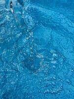 sfondo dinamico spruzzo di chiaro acqua la creazione di vorticoso onda nel blu acqua con goccioline sospeso nel movimento. pulito acqua concetto. foto