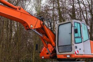 cabina e parte di il boom di un scavatrice contro il sfondo di alberi. foto