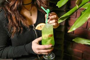 donna Tenere un' verde bevanda nel sua mano a un' bar foto