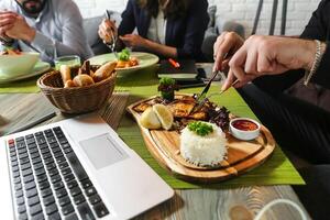 gruppo di persone seduta in giro un' tavolo mangiare cibo foto