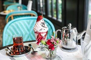 tavolo con tazza di ghiaccio crema e vaso di fiori foto