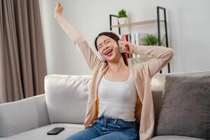 un' donna è seduta su un' divano e ridendo mentre ascoltando per musica foto