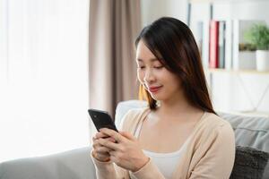 un' donna è seduta su un' divano e guardare a sua cellula Telefono foto