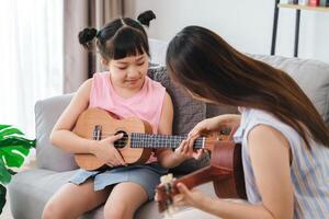 un' donna è insegnamento un' giovane ragazza Come per giocare il ukulele foto