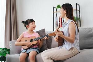 un' donna e un' bambino siamo seduta su un' divano, con il donna giocando un' ukulele foto