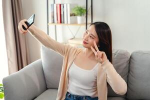 un' donna è seduta su un' divano e assunzione un' autoscatto con sua cellula Telefono foto