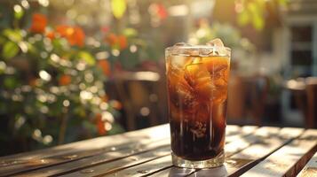 ghiacciato caffè, avvicinamento, con caffè ghiaccio cubi e un' spruzzo di mandorla latte, nel un' alto bicchiere, su un' soleggiato all'aperto tavolo. foto