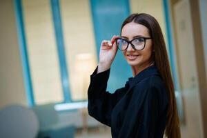 sorridente simpatico ragazza sembra a telecamera e indossa moderno spettacoli. femmina nel spettacoli regali Prodotto per il telecamera. avvicinamento. foto